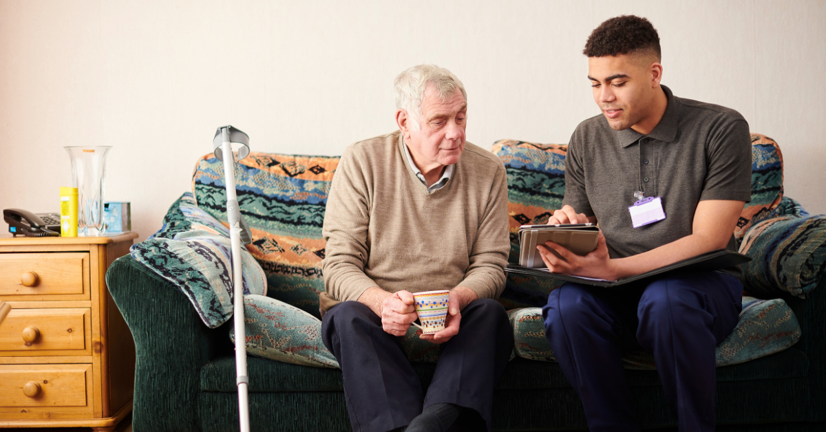 A male Support Worker speaking with an elderly man