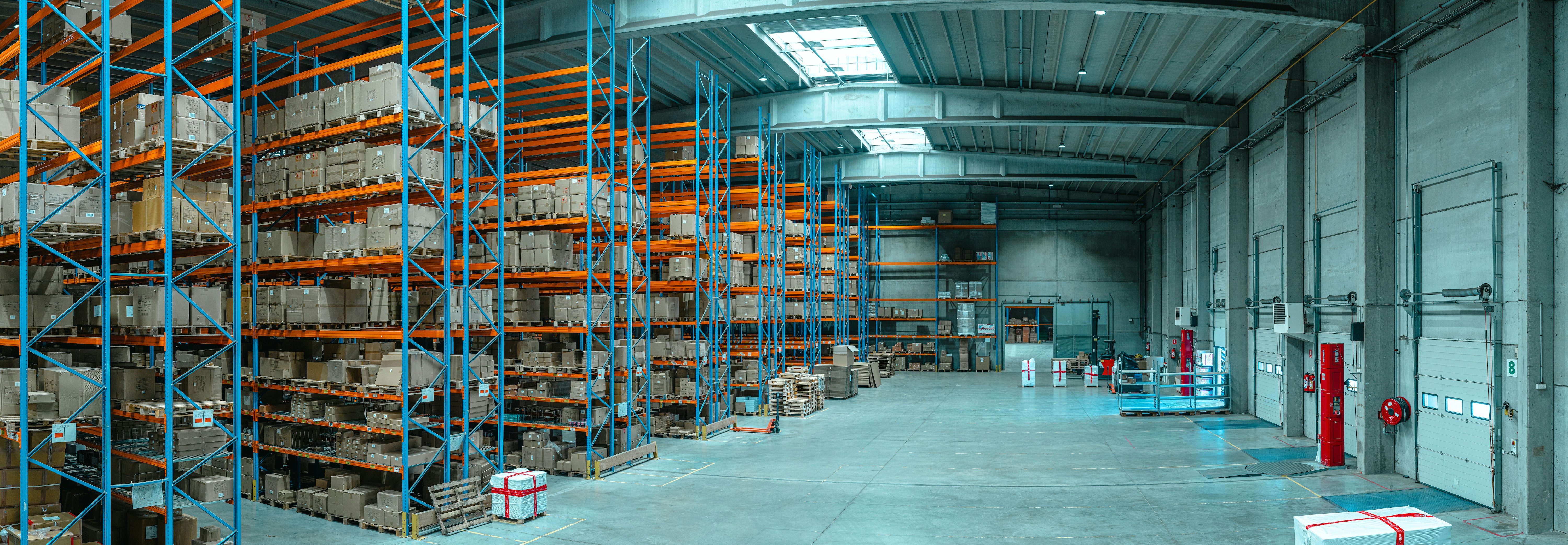 Interior of a large warehouse with tall storage racks filled with boxes and wide aisles.