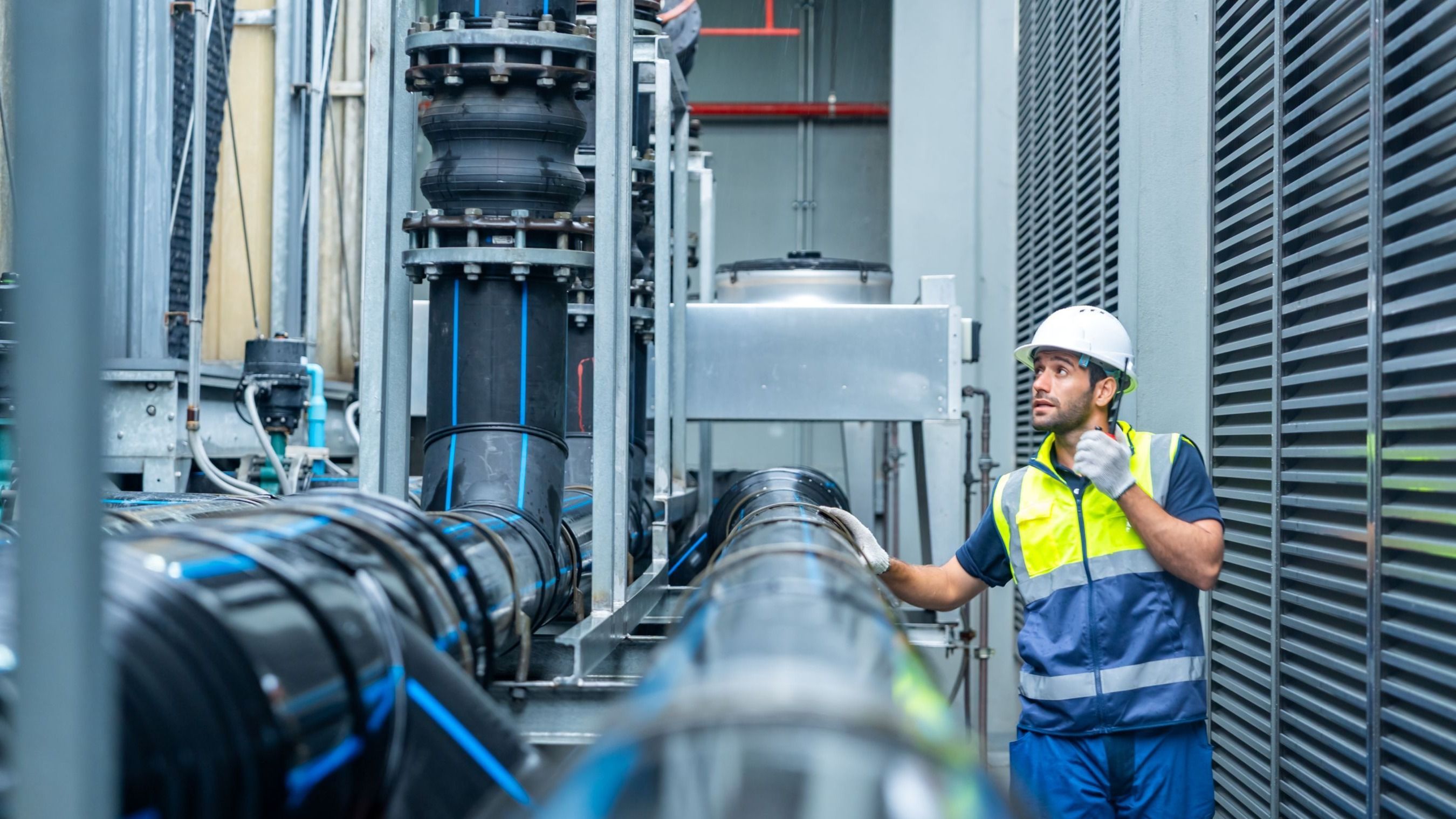 Industrial engineering technician worker working maintenance building exterior plumbing systems. Male engineer in safety uniform