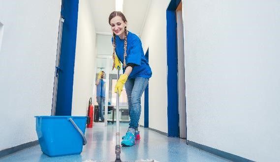 Smiling cleaner mopping floor