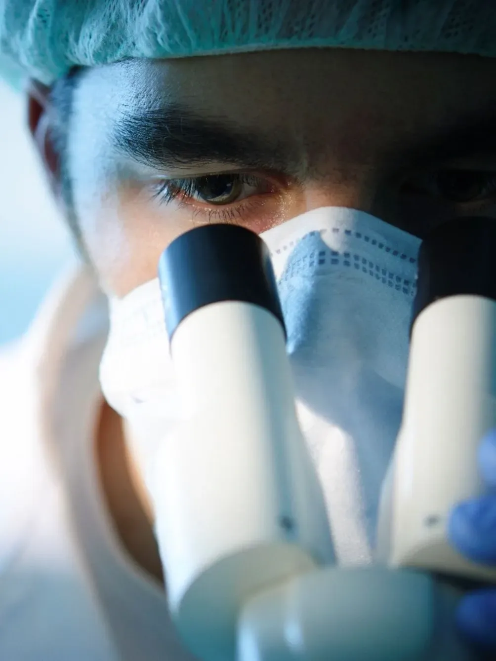 man looking down microscope