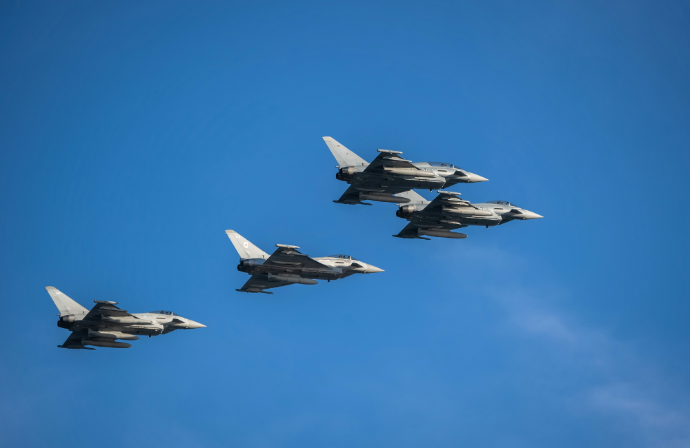 Four military fighter jets flying in formation against a clear blue sky