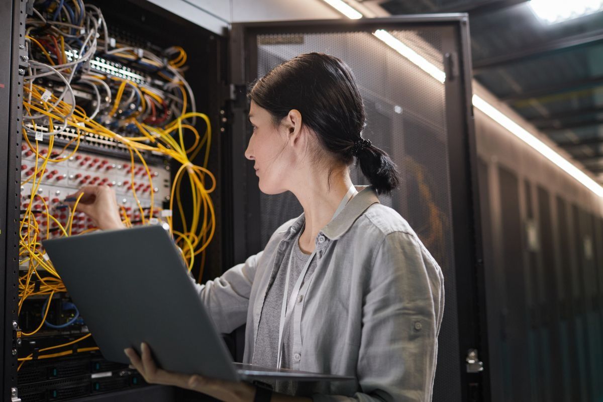 Female network technician working at a server within a data centre