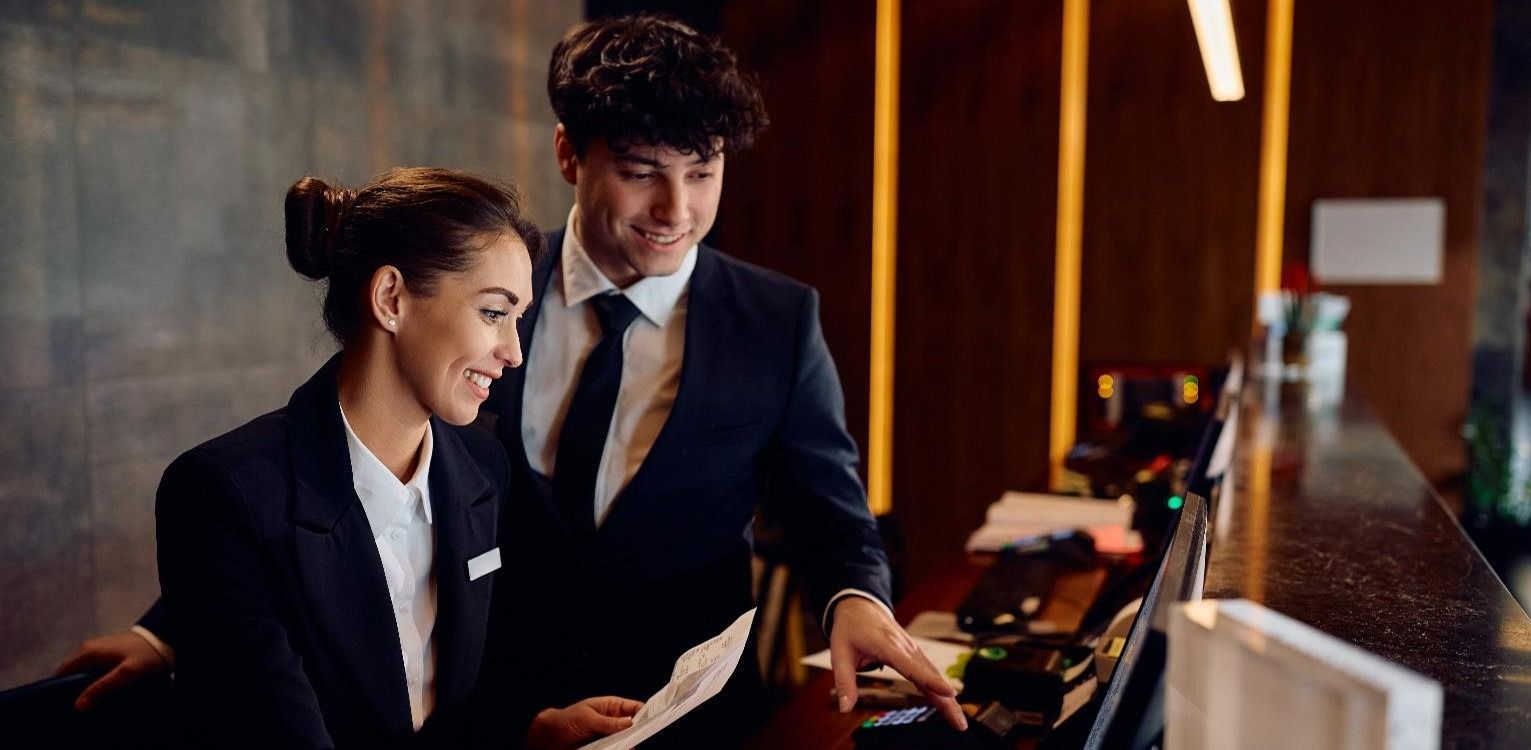 Hotel receptionist smiling and using a computer