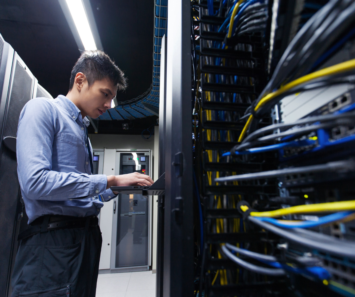Data Centre Technician on laptop in server room