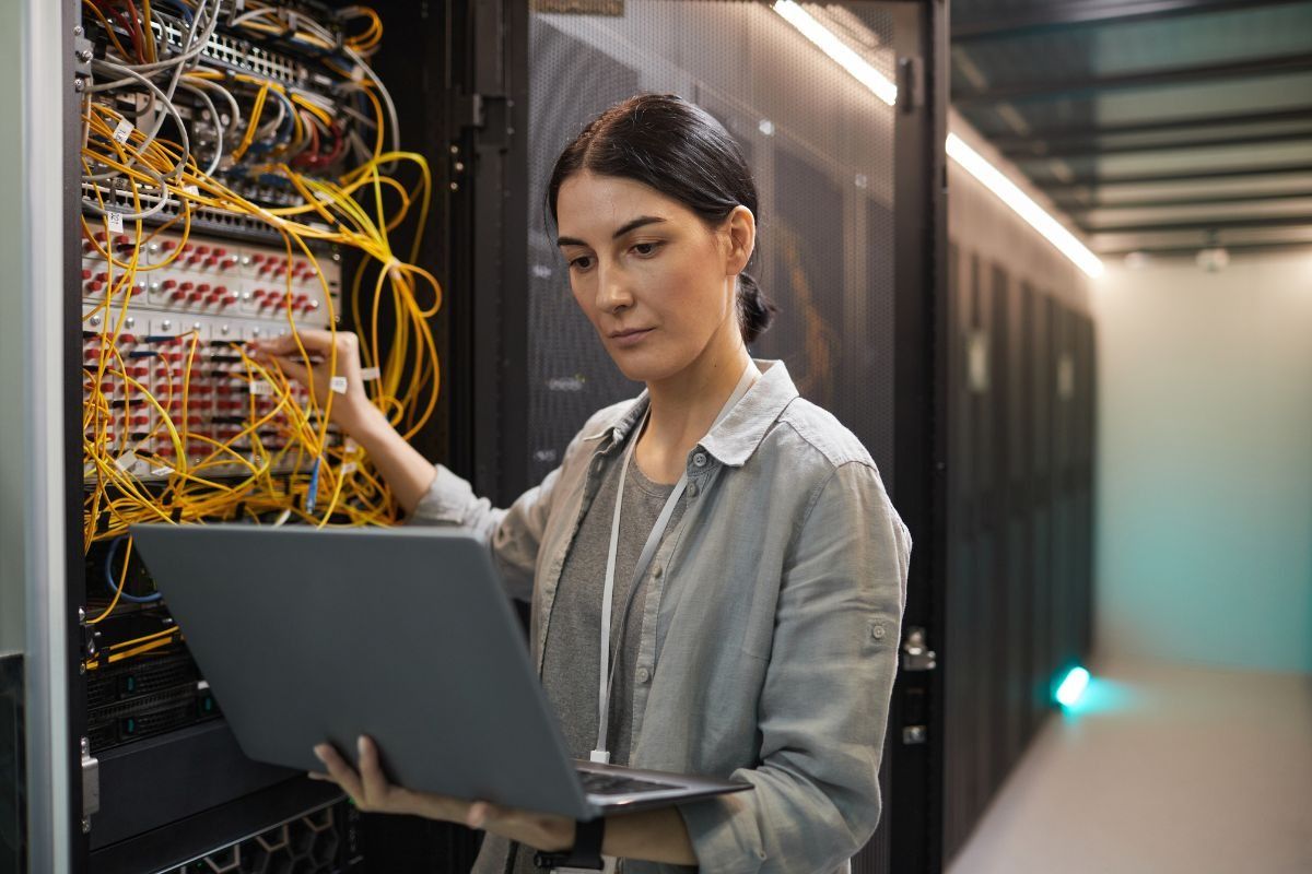 female network technician inspecting servers at a data centre