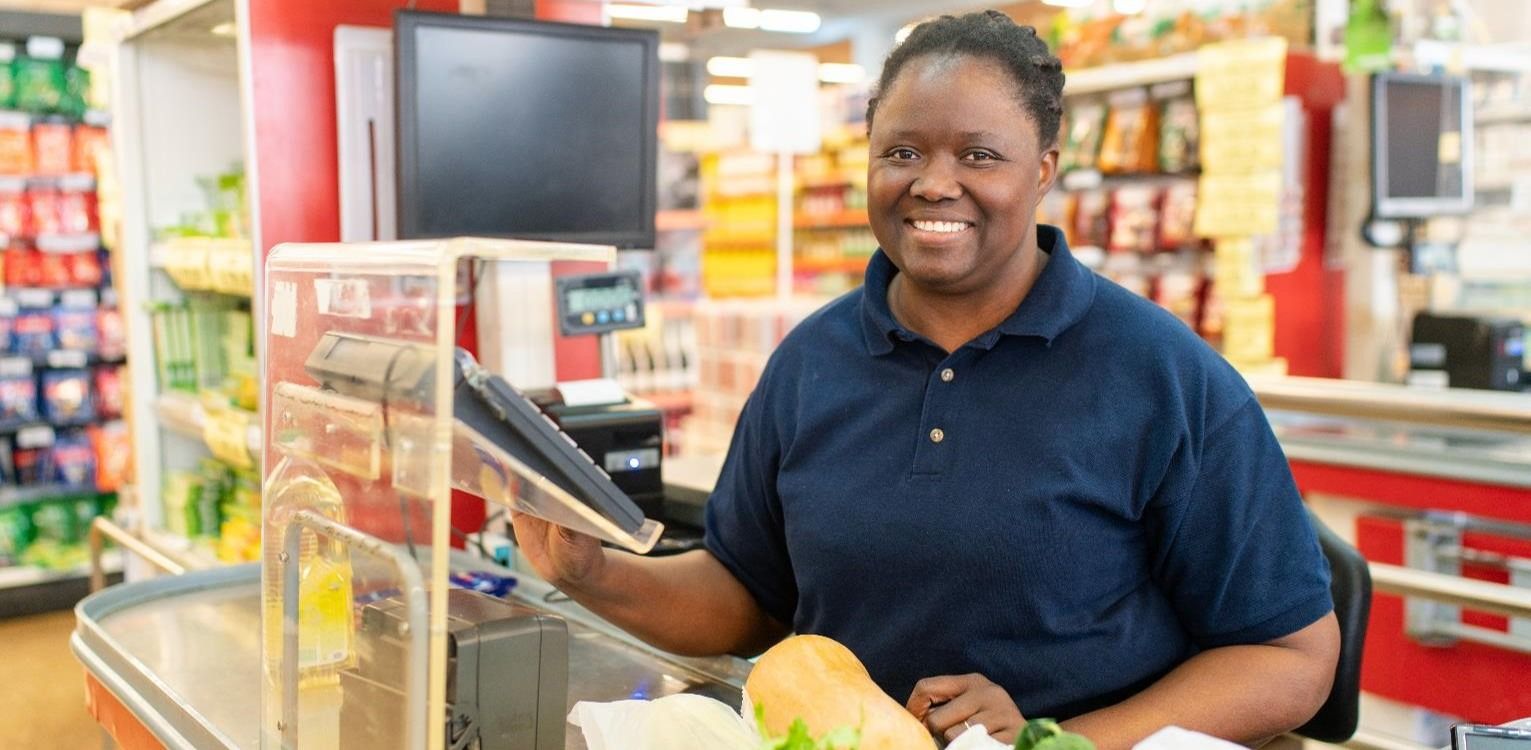 A person standing behind a counter in a grocery store