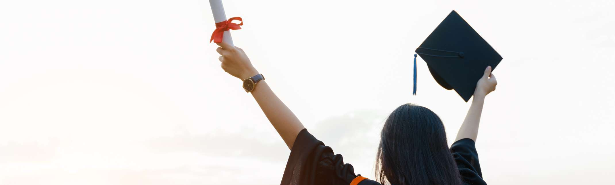 A person holding up their graduation cap and diploma