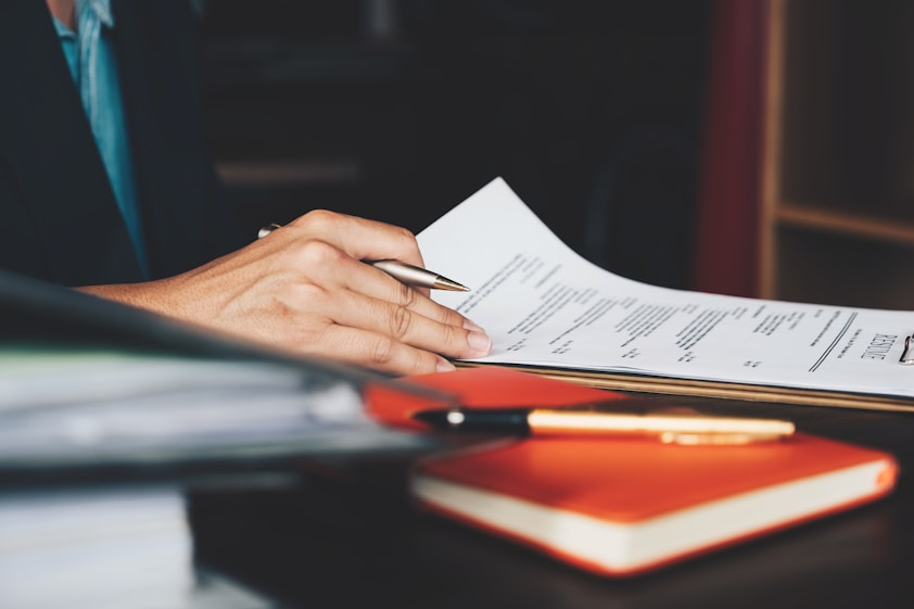 A person writing on a document with a pen