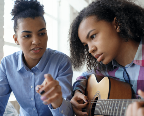 Girl being taught guitar by her Support Worker