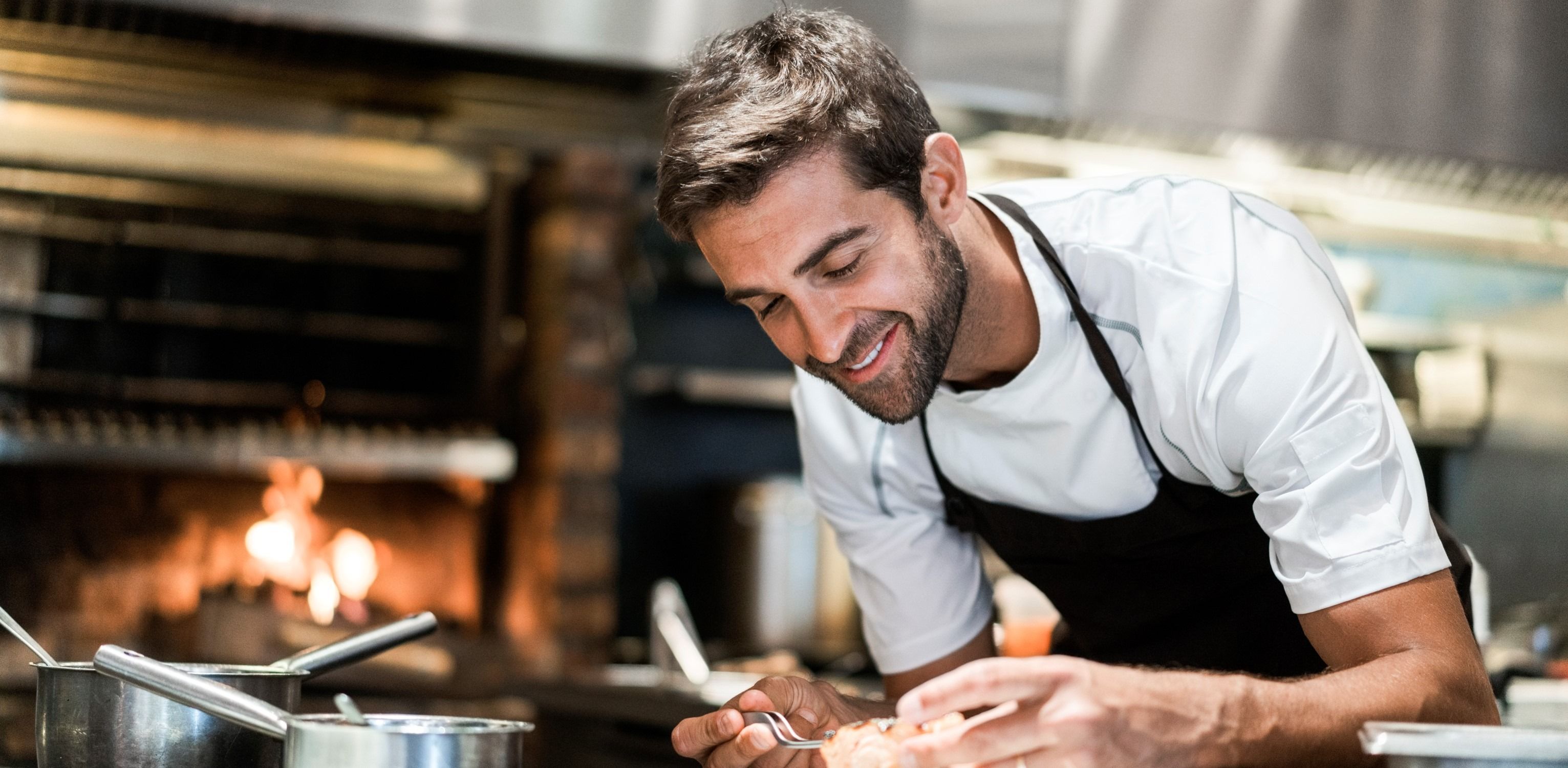 A smiling commis chef plating food