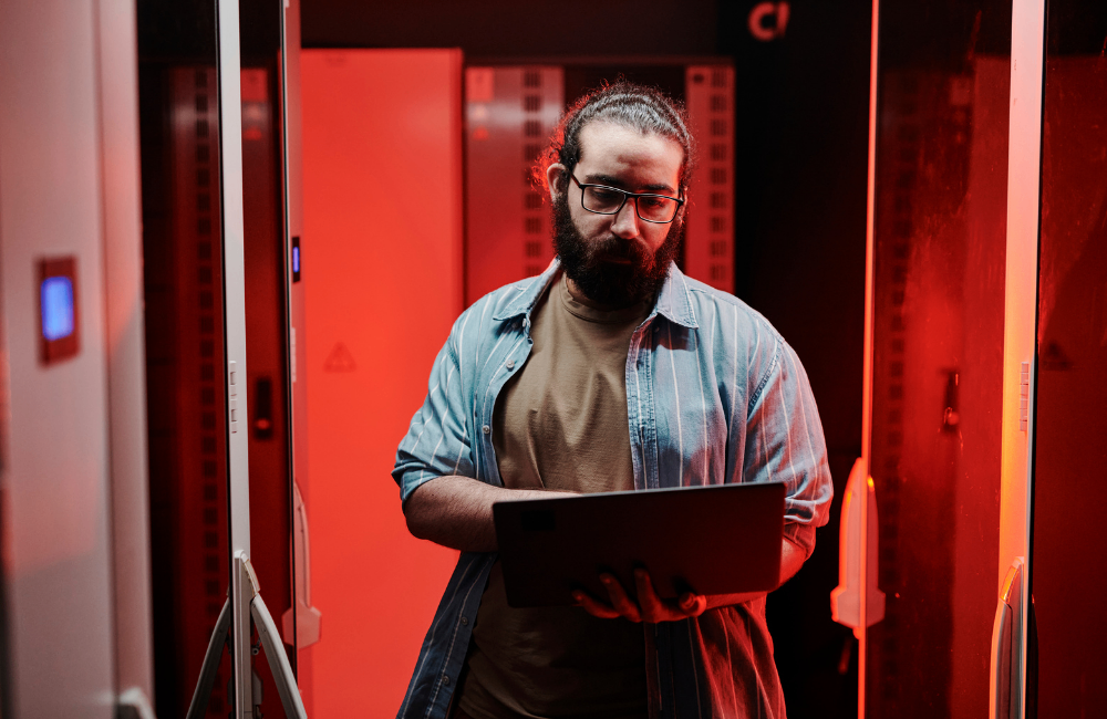 cybersecurity recruitment professional working on laptop in red data cecntre 