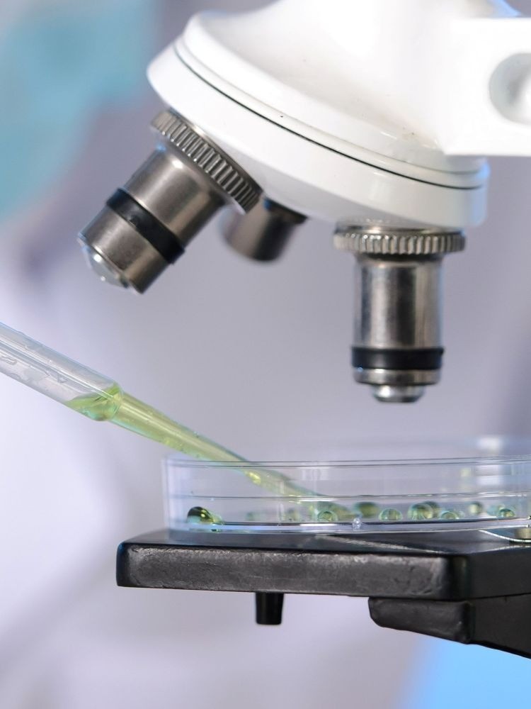 green liquid in pipette and petri dish under microscope