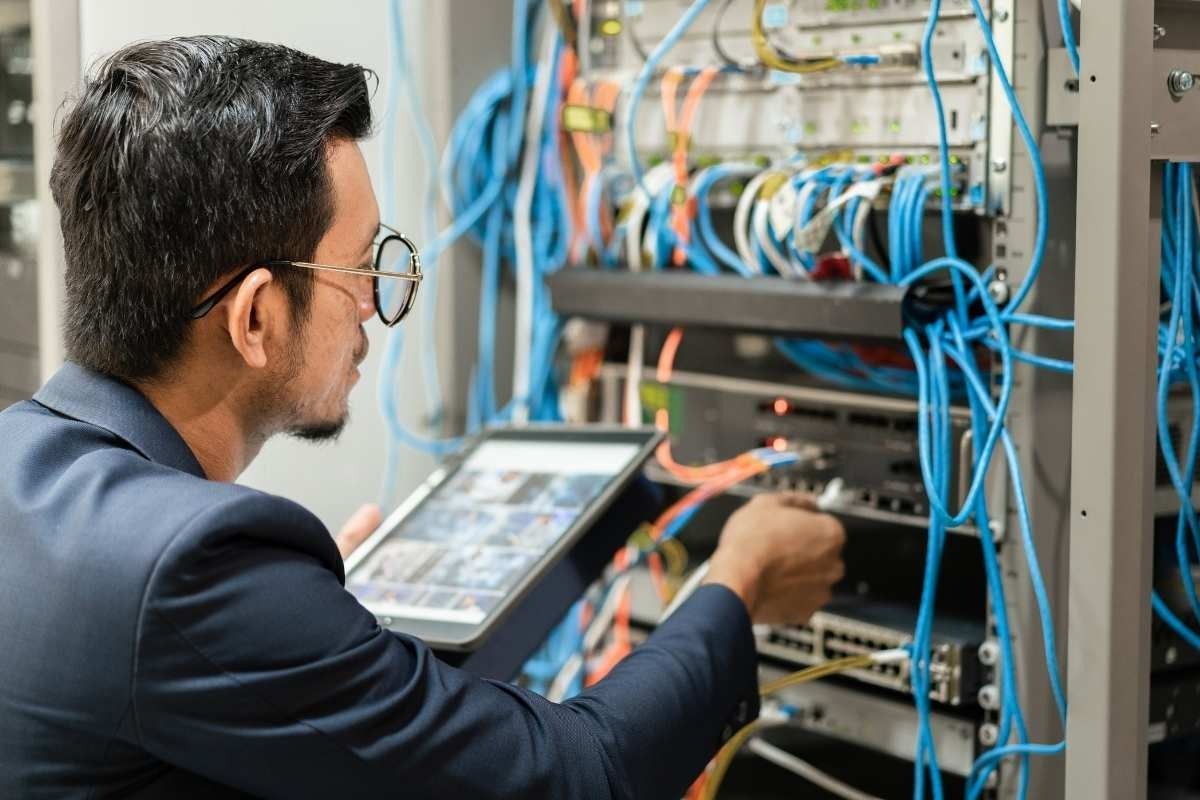 Male network cable technician at server