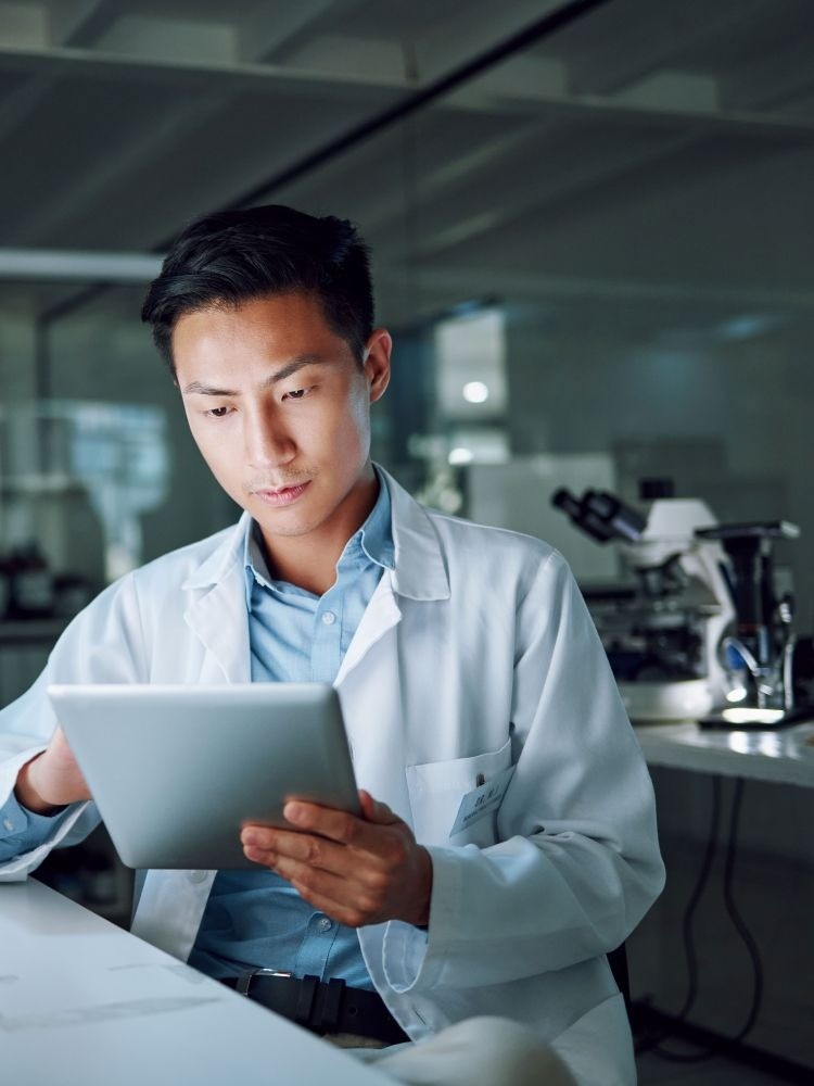 male scientist in lab coat looking at digital tablet