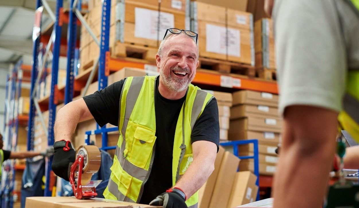 Warehouse worker tapping box smiling