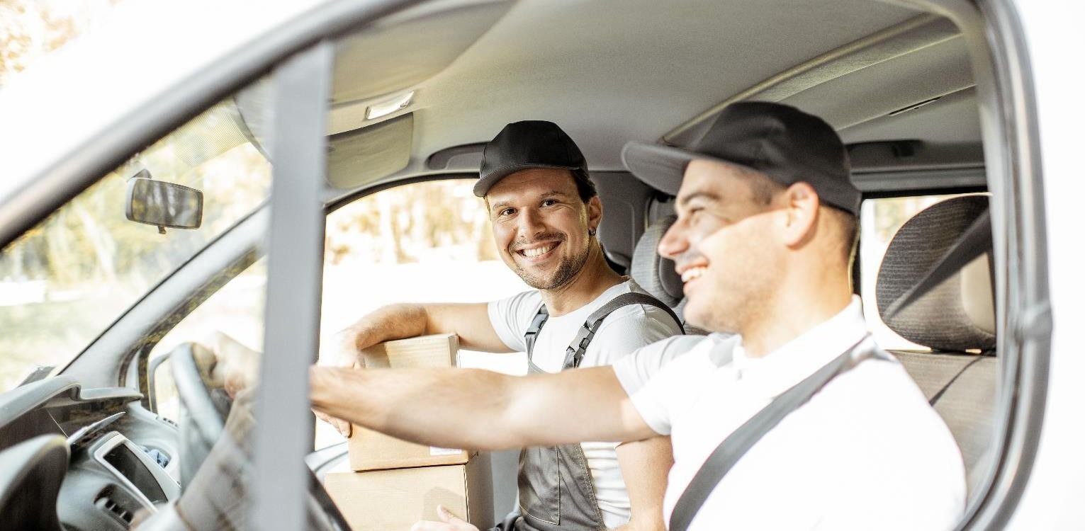 A driver and driver's mate smiling in a van