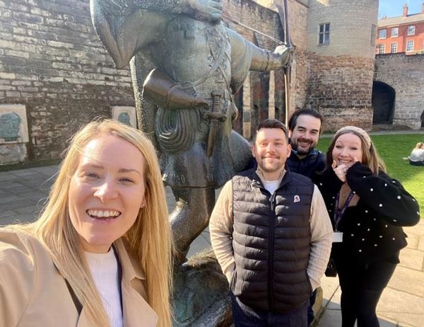 Pareto Nottingham team members smiling with the Robin Hood statue at Nottingham Castle.