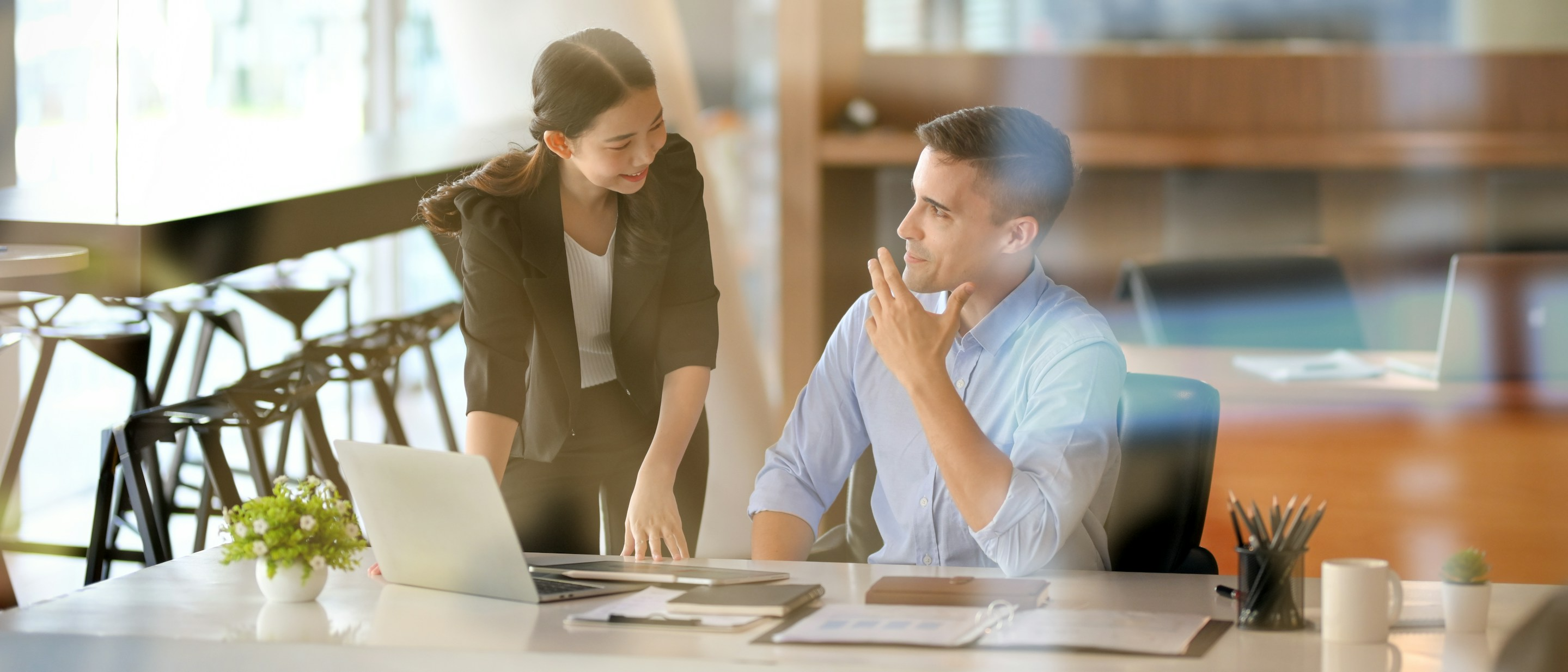 Two people talking and looking at a laptop