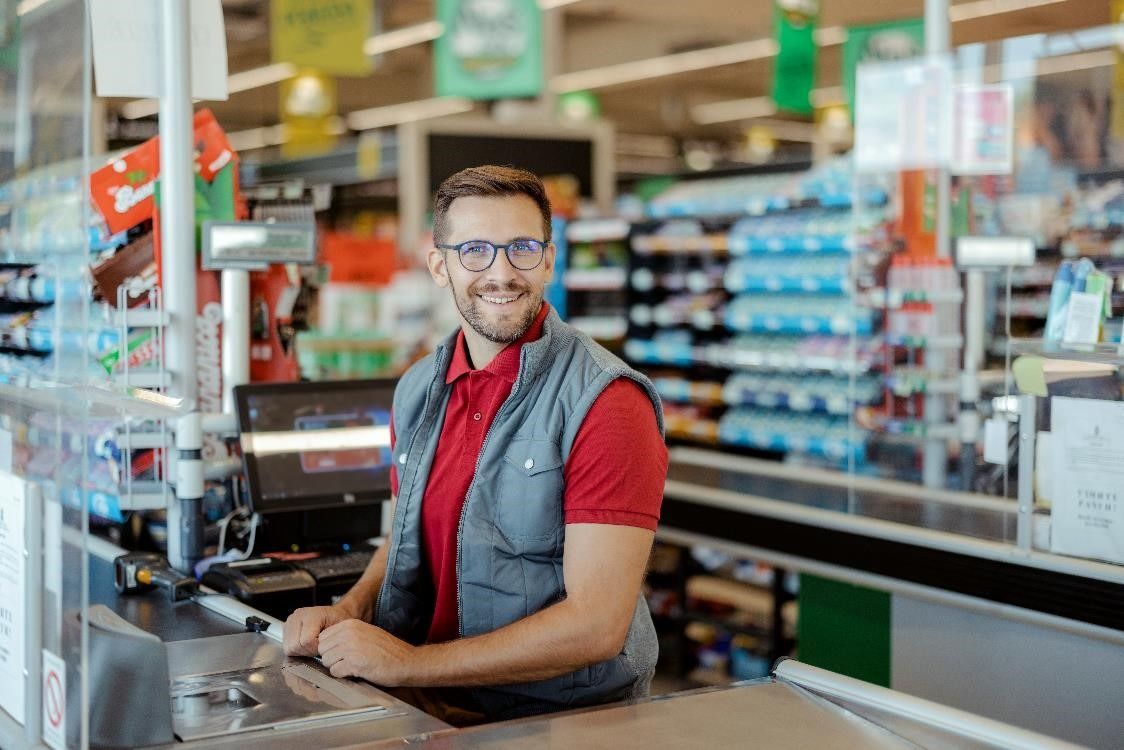 A cashier at the till smiling