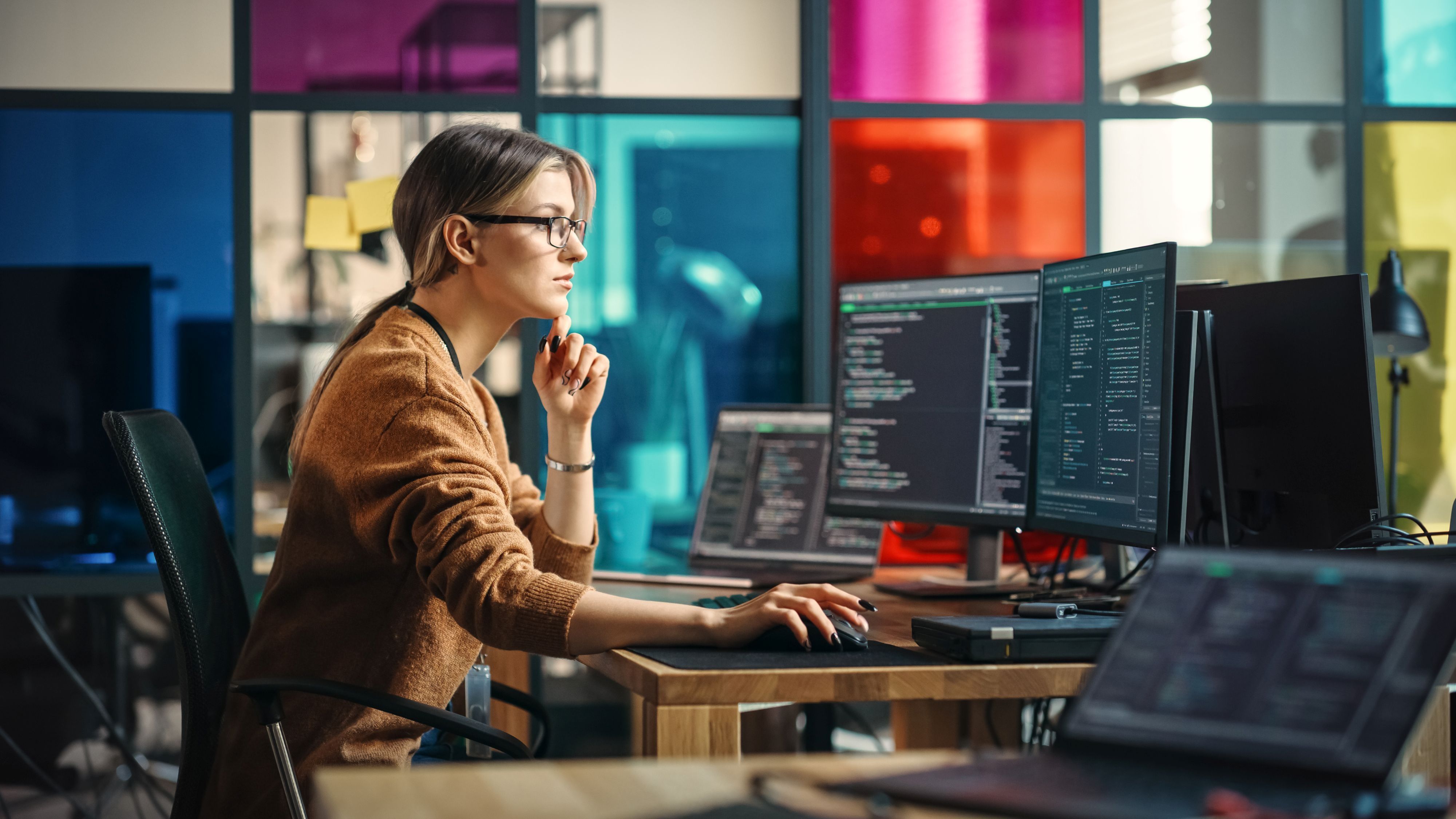 Female software engineer wiring code on a desktop computer