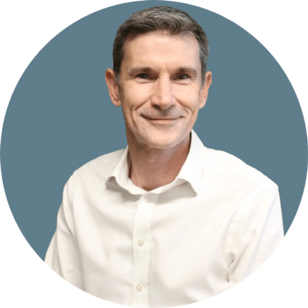 Portrait of Nick Eaves, our Chief Customer Officer and Co-founder of Stanton house in a white shirt against a blue background