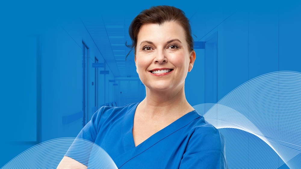 Confident medical professional in blue scrubs standing in a modern hospital corridor, symbolizing healthcare expertise and approachability in Ireland.