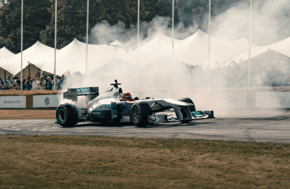 Formula-style race car performing a demonstration run with smoke effects at a motorsport event