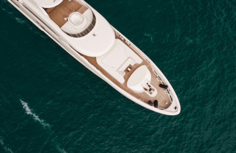 Aerial view of a luxury motor yacht cruising through clear blue ocean water