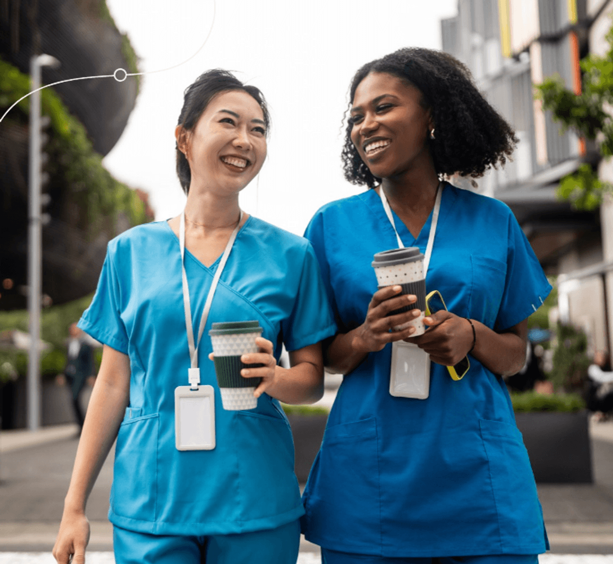 Two healthcare professionals in blue scrubs walking outdoors