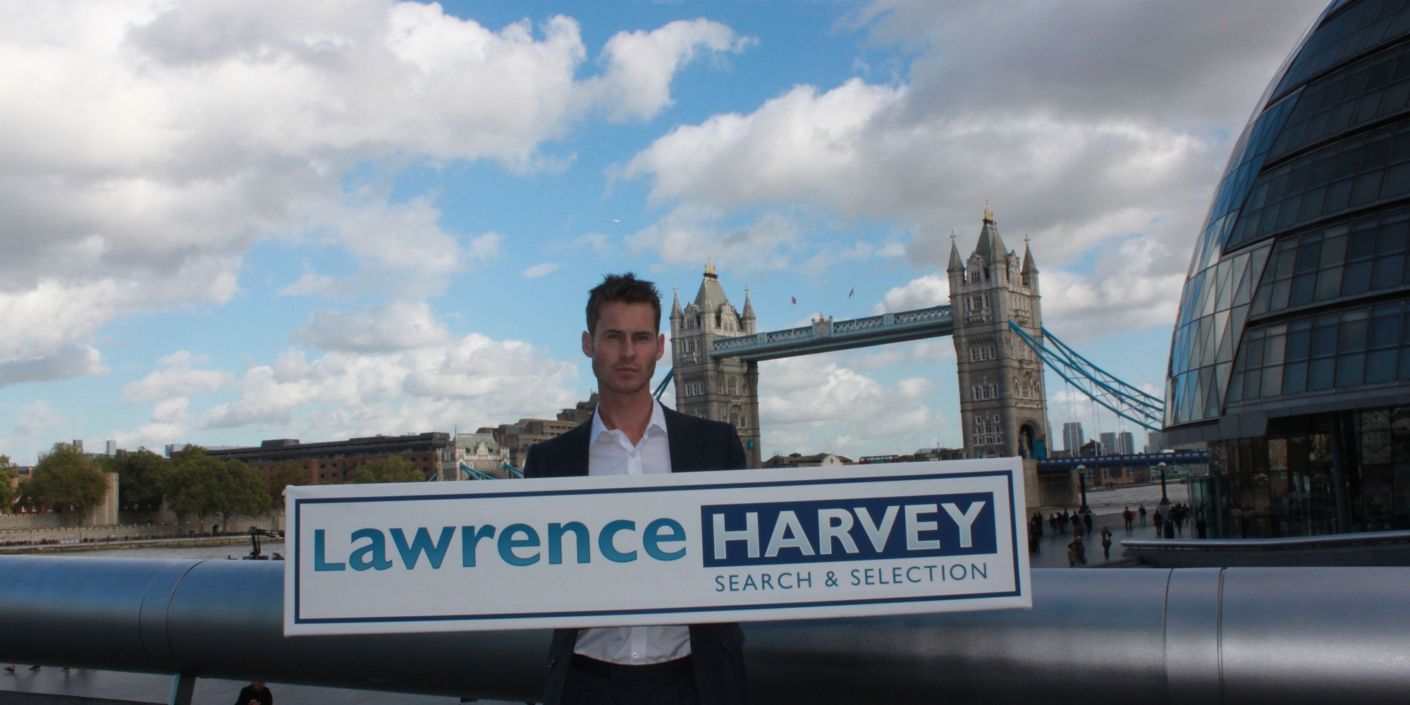 Tom Glanfield holding Lawrnece Harvey sign in fron of London Bridge