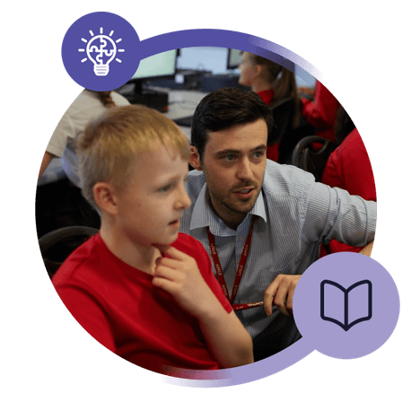 A male teacher helping a male student in a classroom setting.