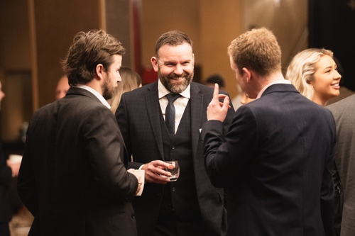 Several men in suits discussing among themselves at a professional gathering.