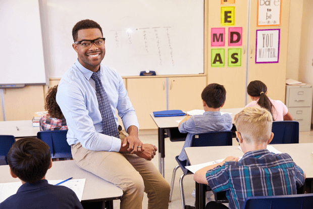Teacher in classroom sat o students desk
