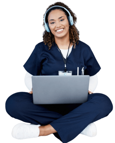 Nurse in navy scrubs sitting cross-legged with a laptop and headphones, reading a healthcare blog online.