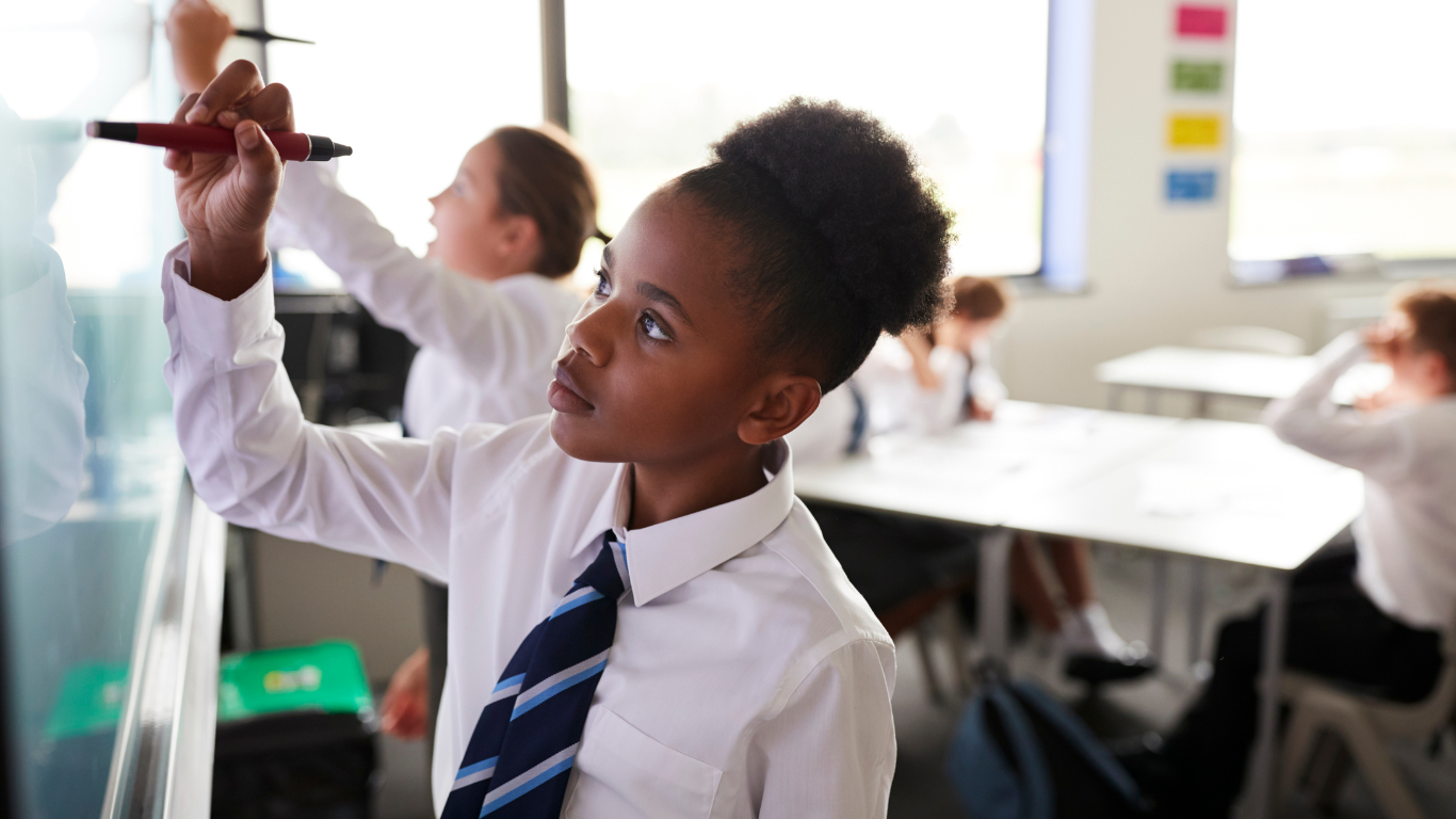 A Year 7 Secondary School pupil writing on a whiteboard in class