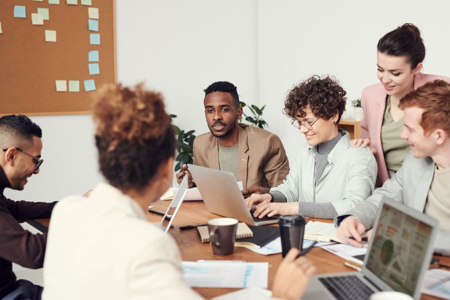 Group of business people having a meeting around a large desk with laptops