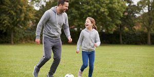 A Support Worker playing football with a young girl