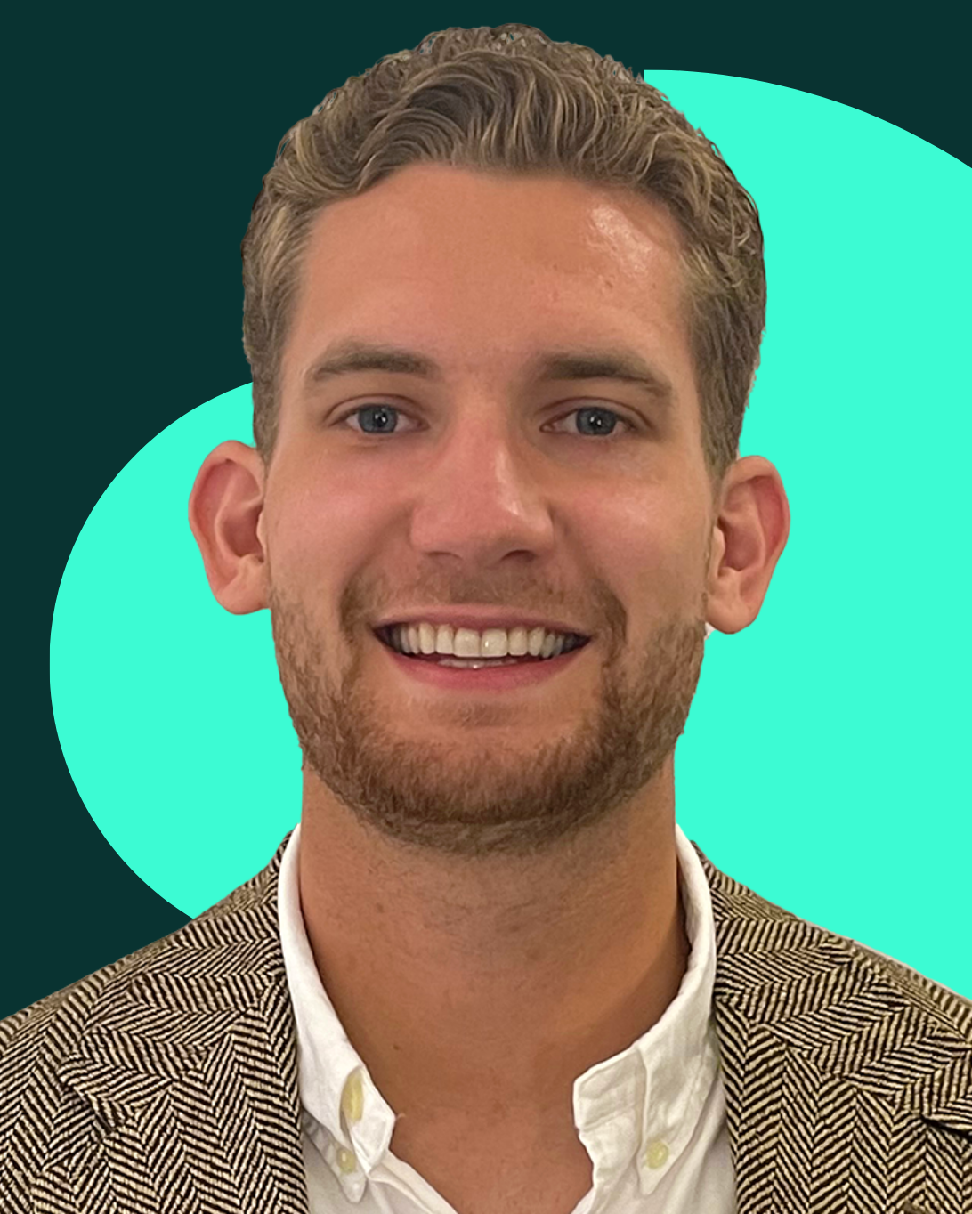 Portrait of Kieran Aldred smiling, with curly hair and trimmed beard, wearing a patterned blazer over a white shirt.