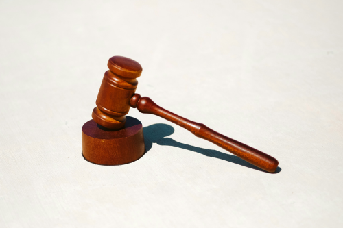 Close-up of a wooden gavel placed on a sound block, commonly associated with courts, legal decisions, and formal rulings.