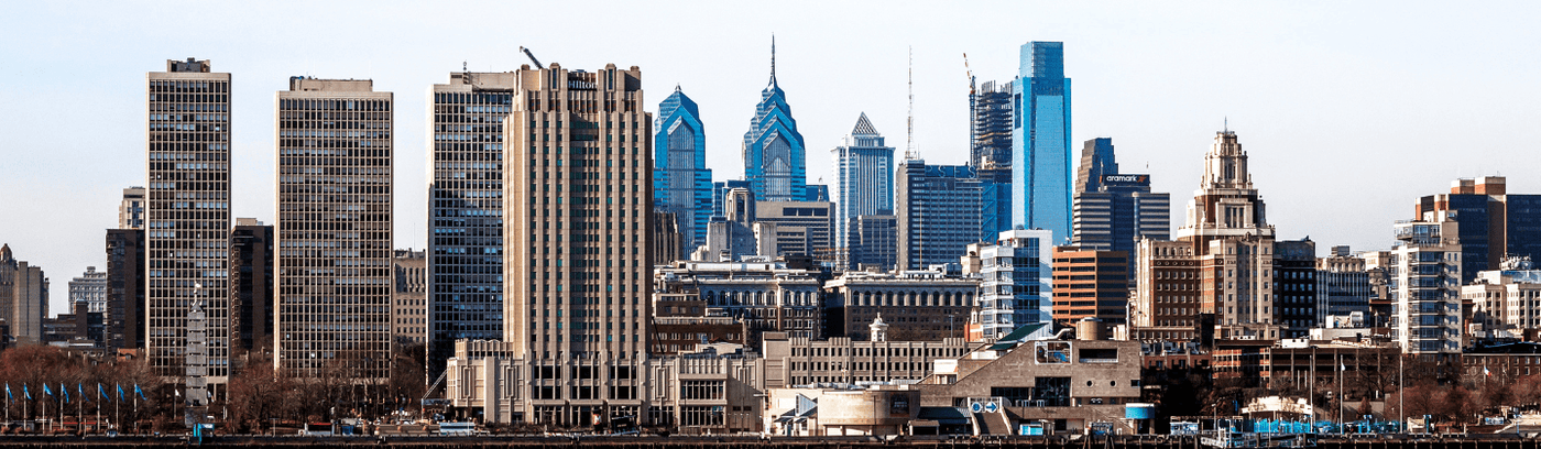 Philadelphia skyline illuminated at night, showcasing tall buildings against a dark sky filled with stars.