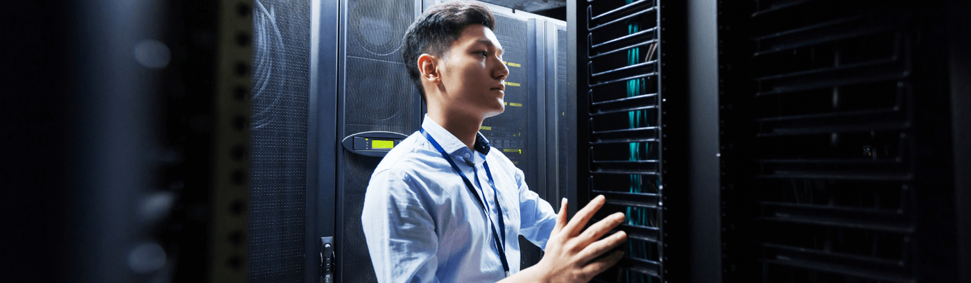 A data engineer in formal attire stands in front of a server, highlighting his role in managing data infrastructure.
