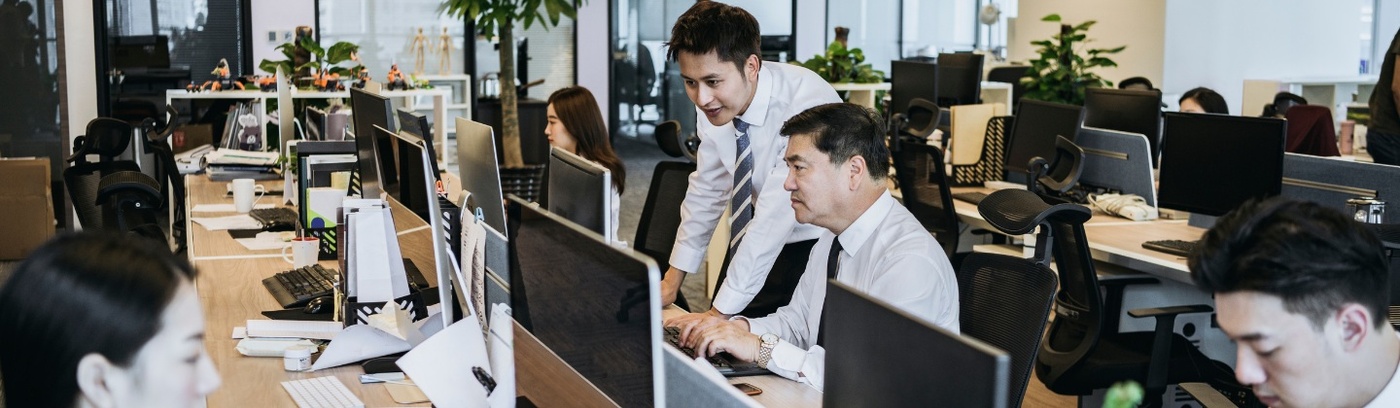 A woman in a business suit engages in conversation with two individuals during a recruitment meeting.