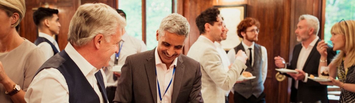  A group of professionals networking at a business event, enjoying food and drinks in an elegant setting.