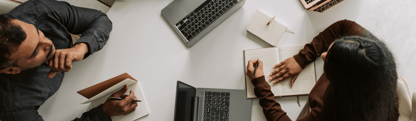 Several people gathered at a table, focused on their laptops, engaged in a collaborative discussion.