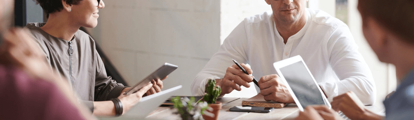A diverse group of individuals seated at a table, each focused on their laptops, engaged in collaborative work.