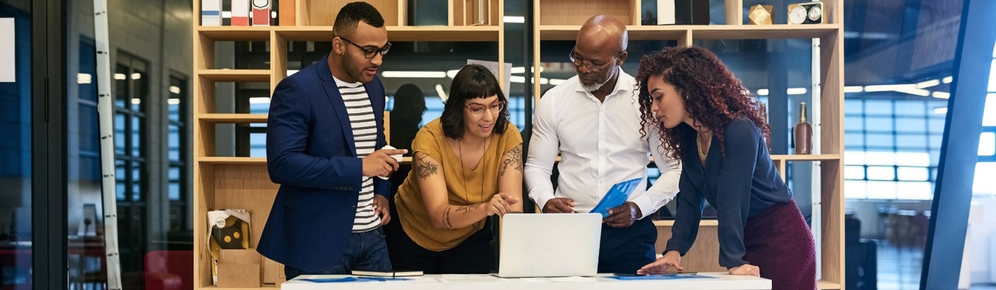 A diverse group of professionals collaborating on laptops in a modern office environment.