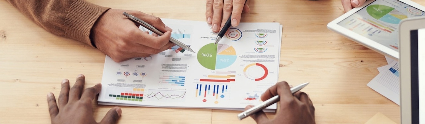 A group of people collaborating on a document featuring various graphs and charts for analysis and discussion.