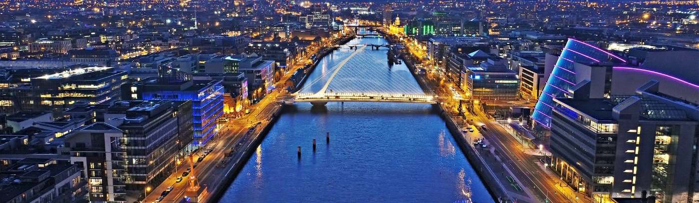 The cityscape of Dublin at dusk, with lights twinkling in the buildings and a beautiful gradient in the evening sky.