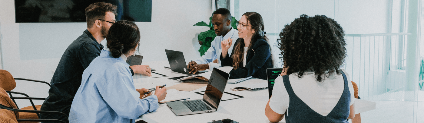 Several individuals seated at a table, focused on their laptops, engaged in a collaborative work session.